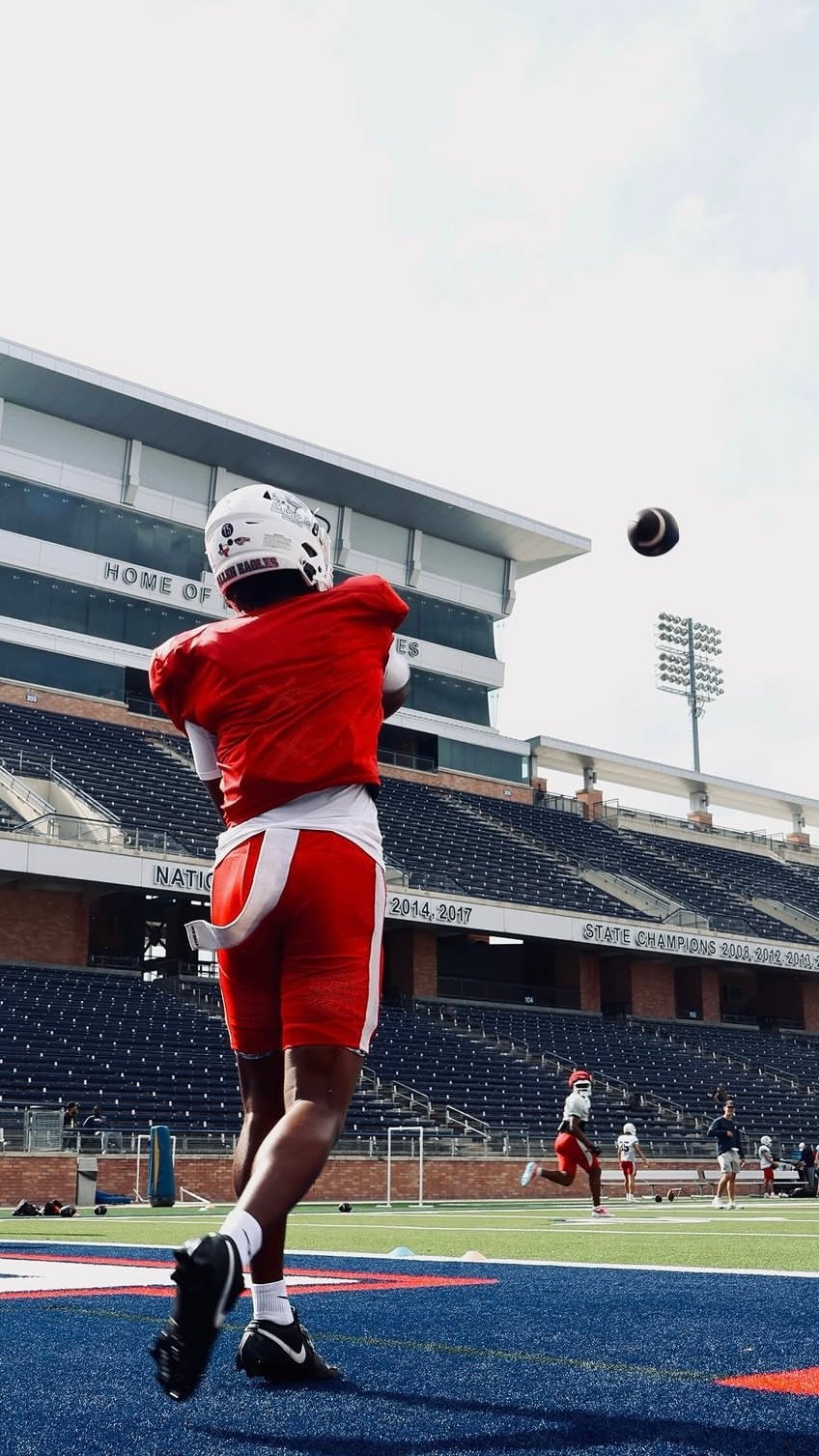 Football player in red jersey throwing ball in stadium