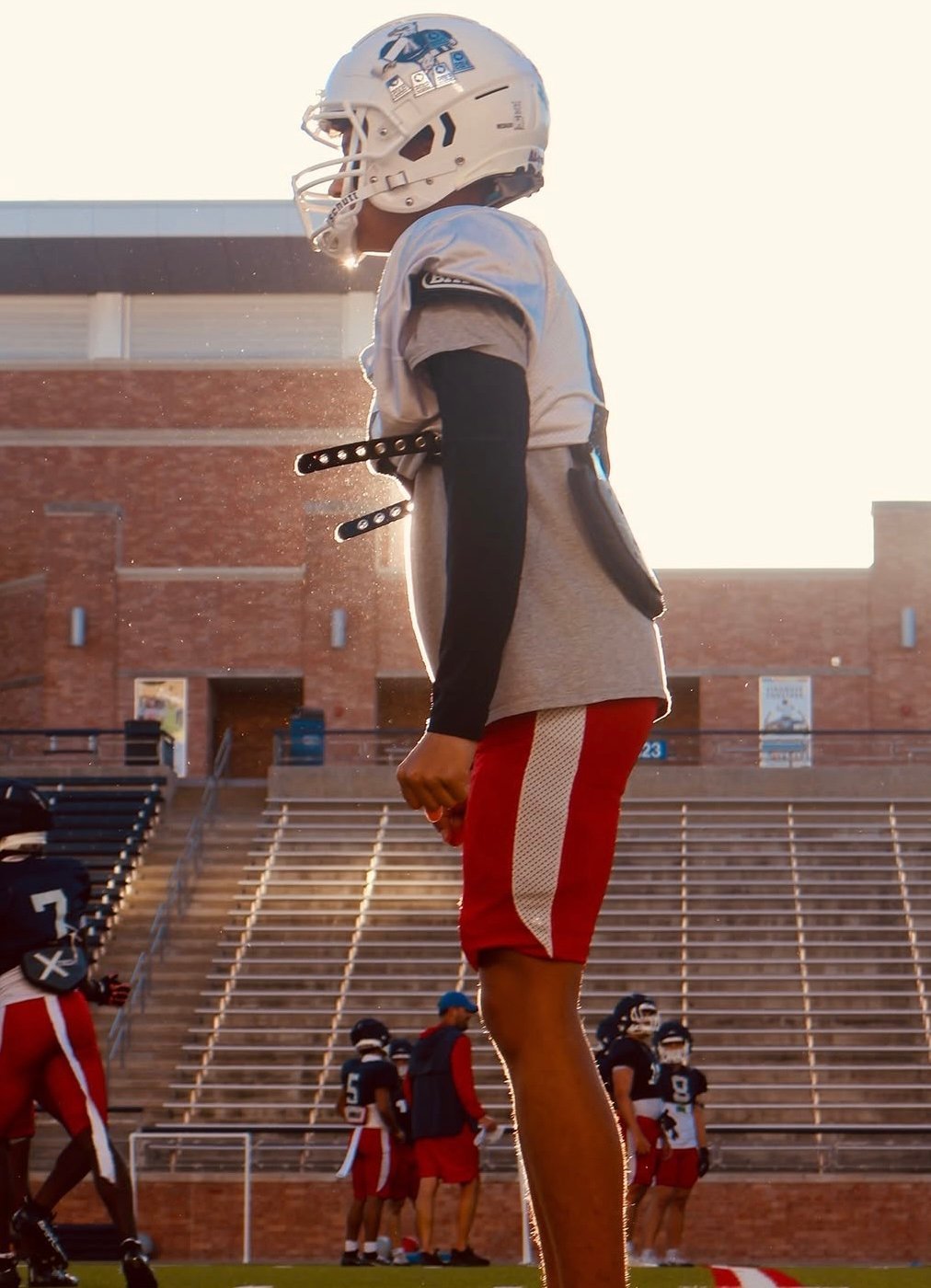 Giant inflatable football player mascot at stadium field during daytime with team players below